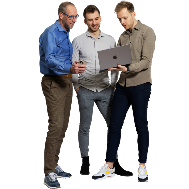 Drie mannen in formele kleding kijken samen naar een laptop. De man links draagt een blauw overhemd, de man in het midden een grijs shirt, en de man rechts een beige blouse. Ze staan ontspannen en zijn bezig met een gesprek over de laptop.